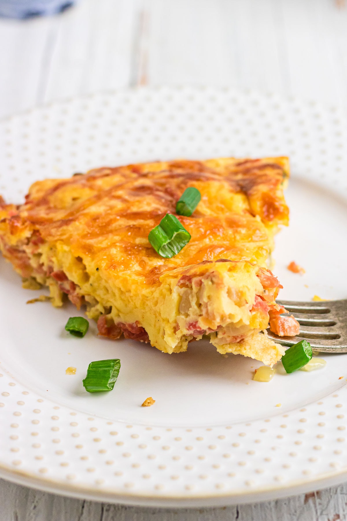 A close-up photo of a slice of zucchini quiche on a plate.