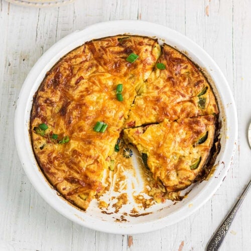 Overhead view of zucchini quiche with a slice removed.