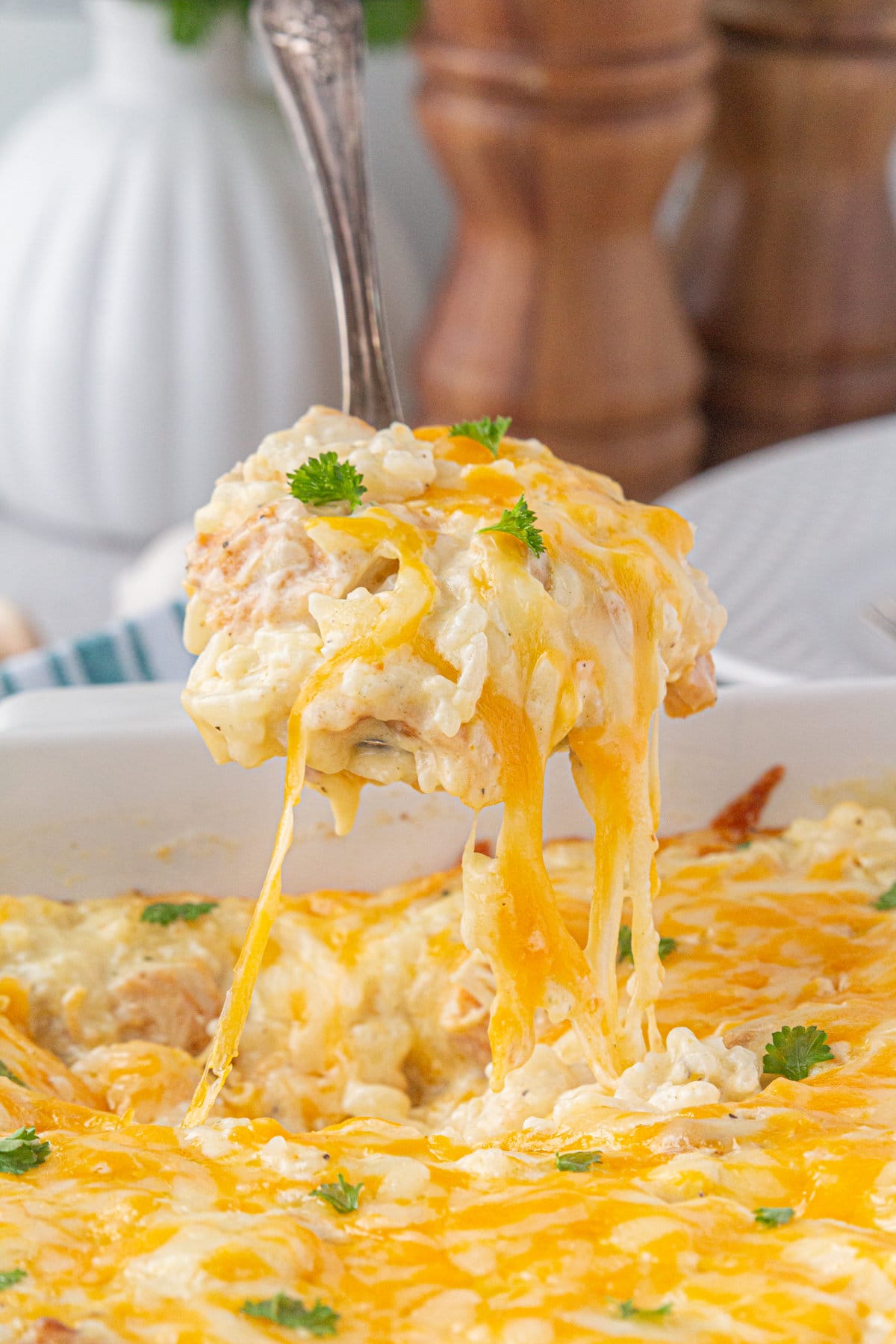 A scoop of angel chicken and rice with strings of cheese hovered over the casserole dish.