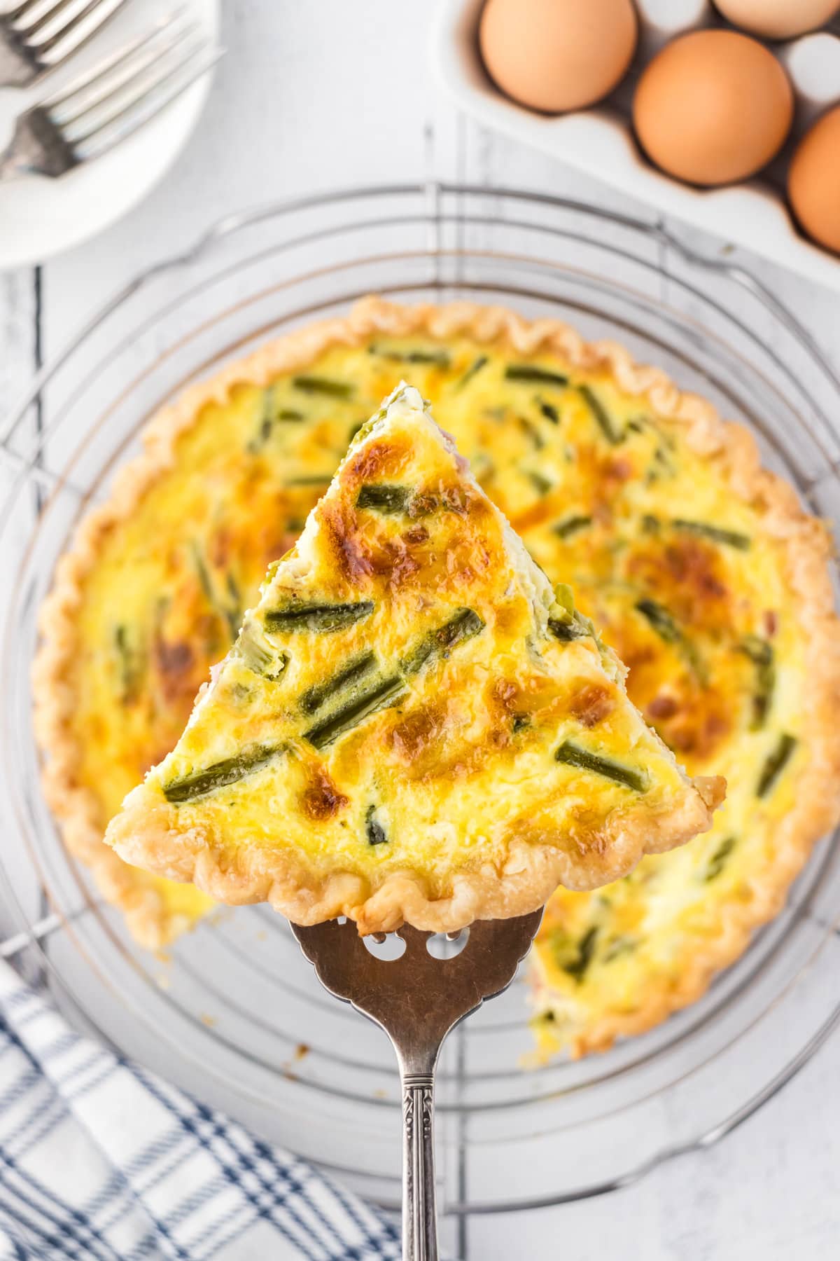 A slice of ham and asparagus quiche on a pie server.