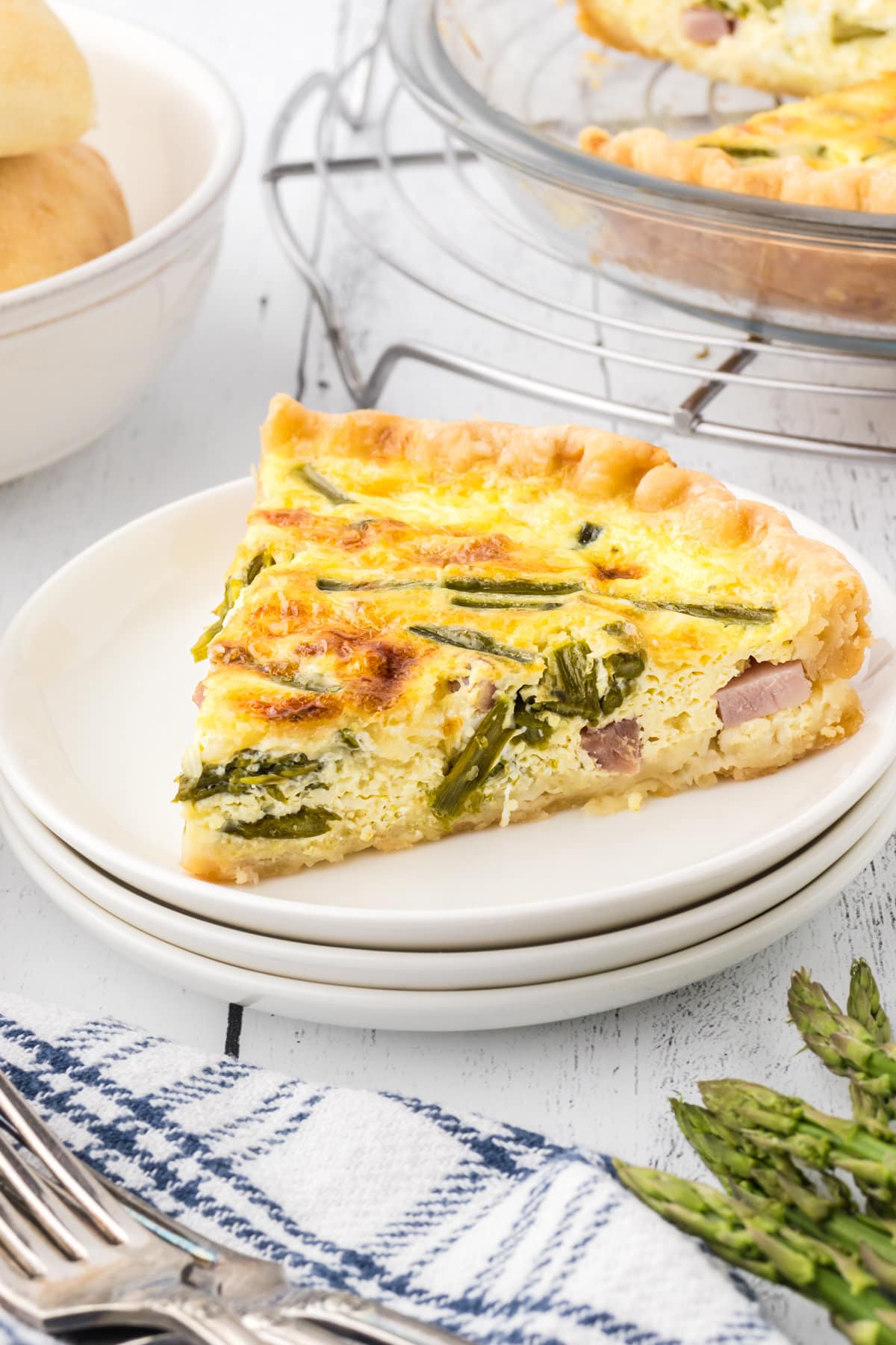 A slice of ham asparagus quiche on a dinner plate.