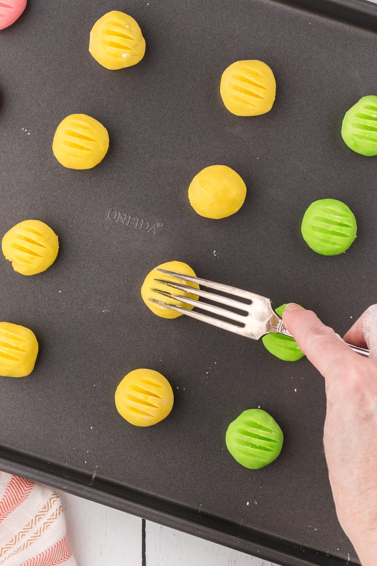 A fork pressed on top of one of the balls of cookie dough.