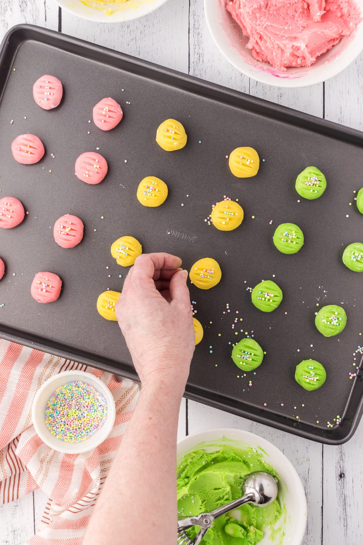 Sprinkling the shaped cookies with nonpareils.