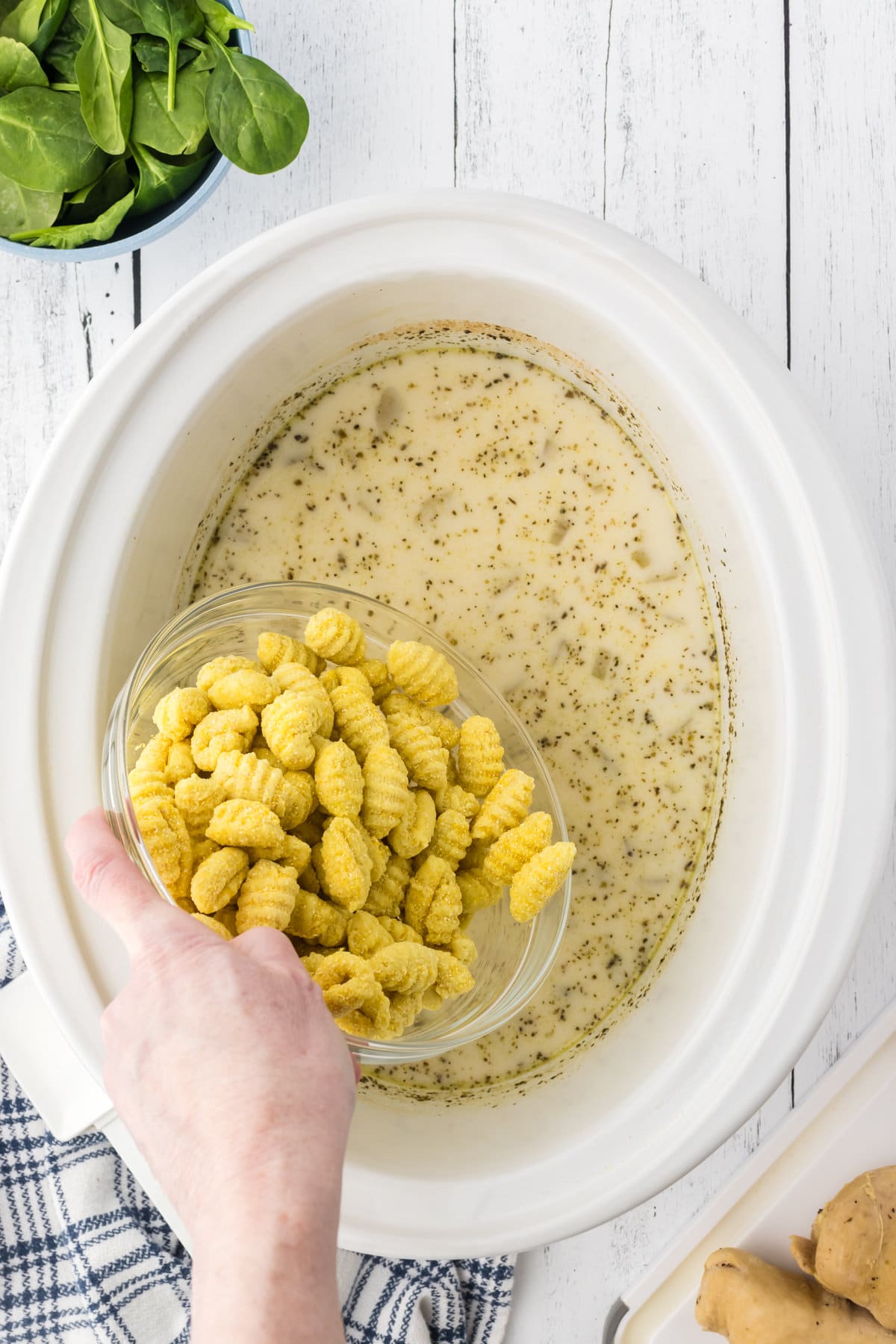 Dumping the gnocchi into the soup in the crockpot.