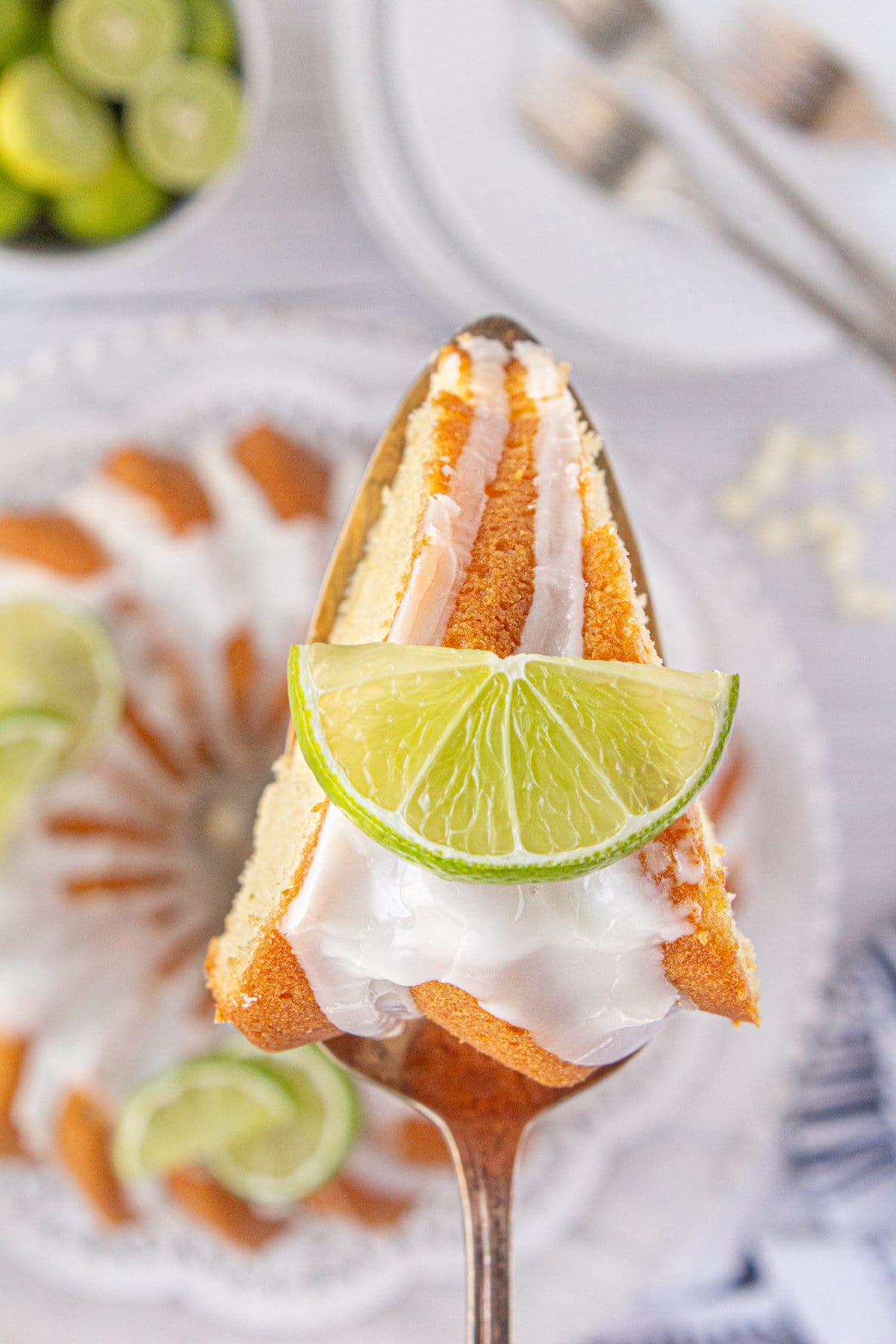 An up-close photo of a slice of white chocolate key lime bundt cake on a cake server.