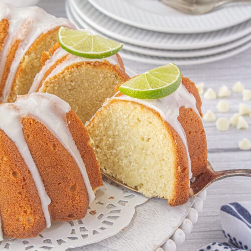 A closeup of a slice of lime bundt cake with a white chocolate glaze on a table.