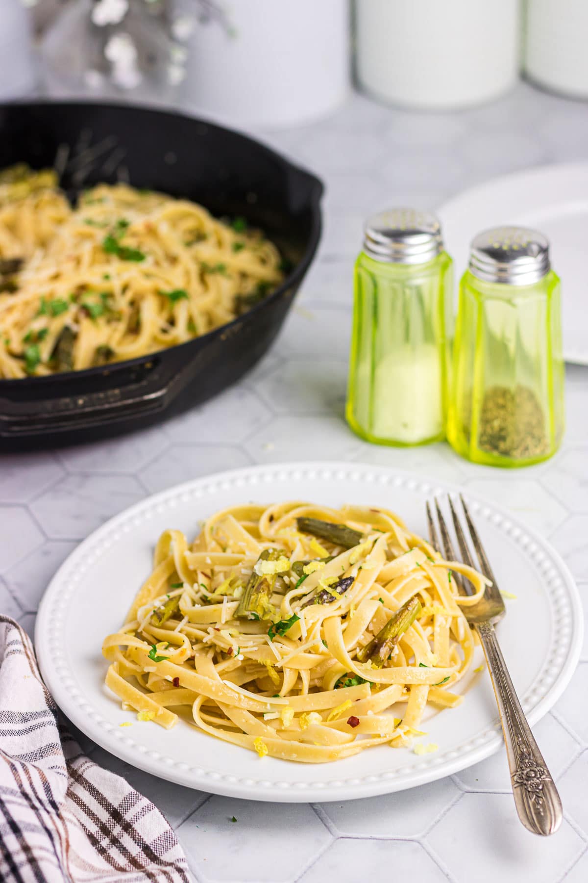 Asparagus pasta with parmesan cheese and herbs on a dinner plate.