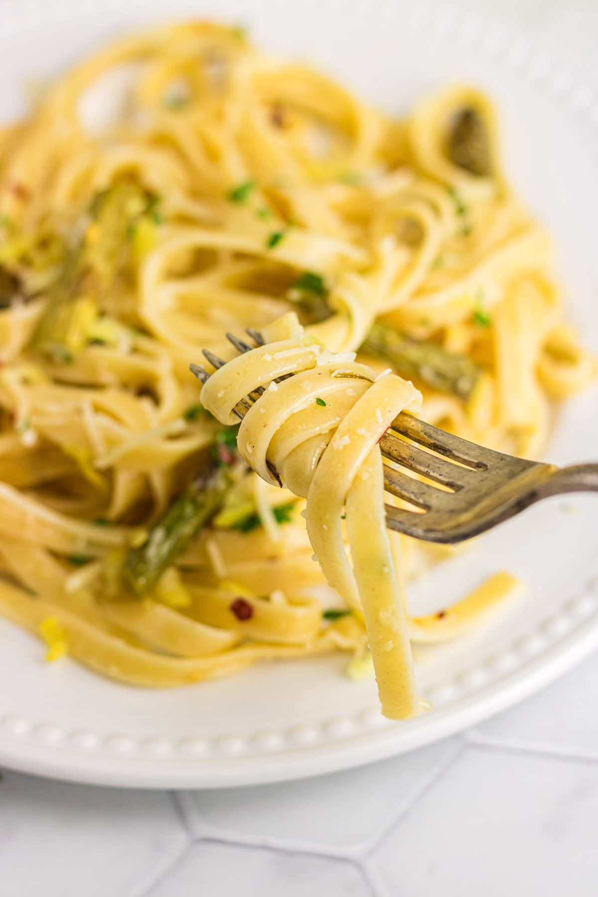 A fork with lemon asparagus pasta twirled around it.