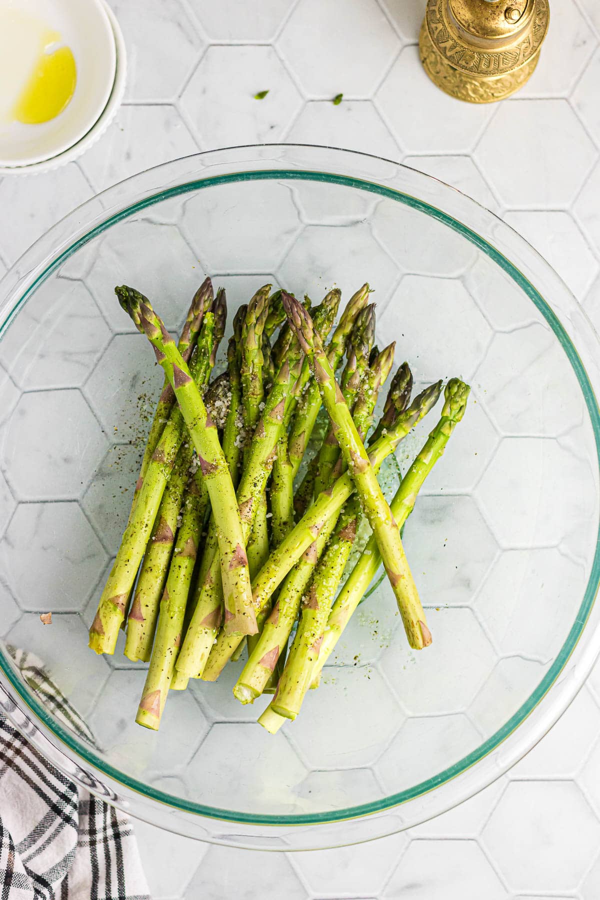 A glass bowl filled with raw asparagus spears.