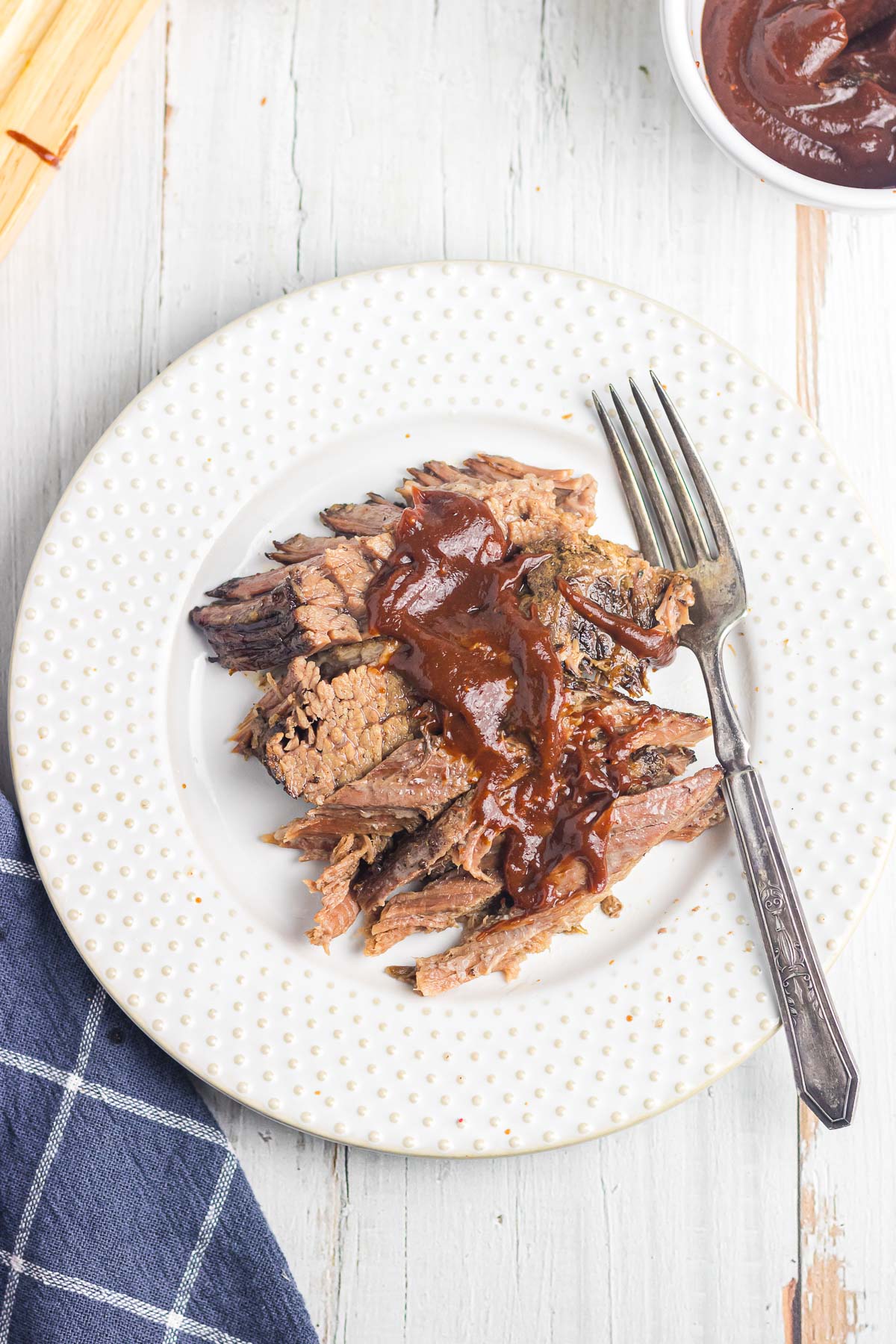 An overhead photo of brisket on a plate with BBQ sauce.