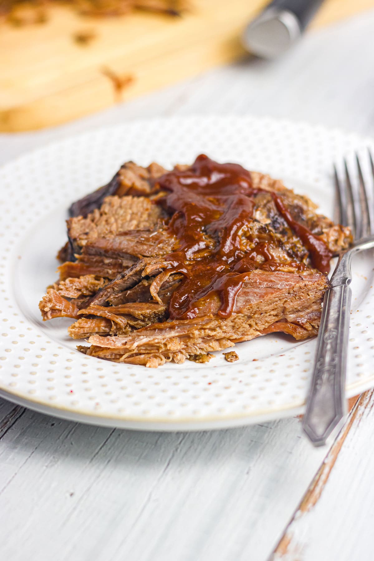 A large plate of brisket topped with BBQ sauce.