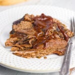 A plate of brisket with bbq sauce on it.