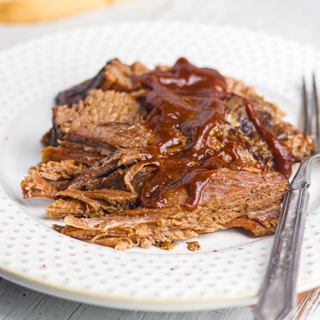 A plate of brisket with bbq sauce on it.