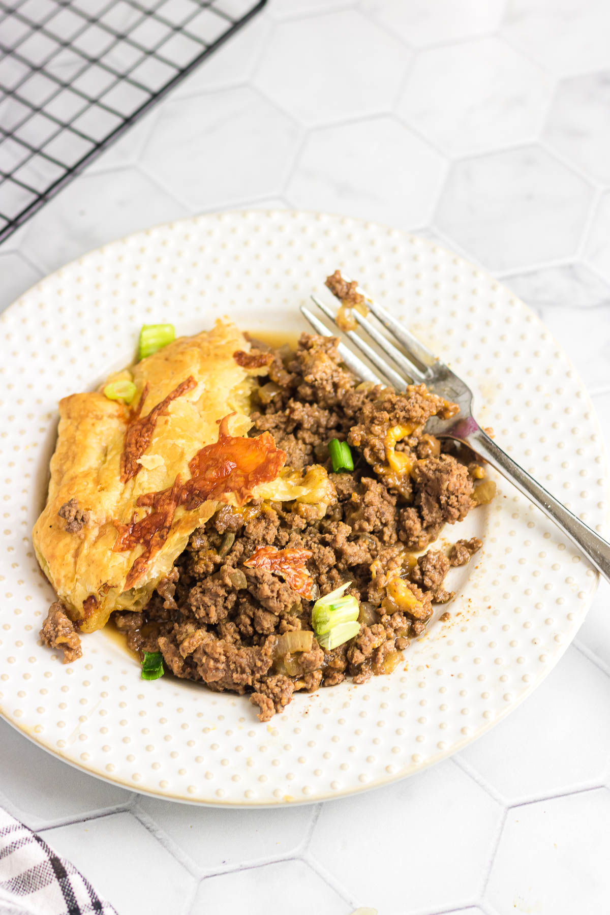 Puff pastry cheeseburger pot pie on a serving plate with a fork.