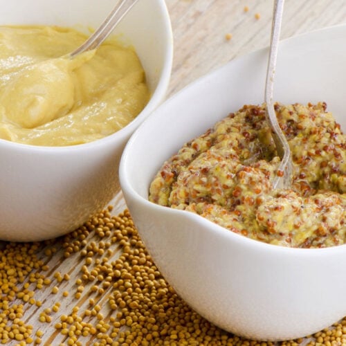 Two dishes of mustard on a table.