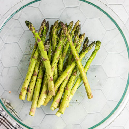 Raw asparagus in a glass bowl.