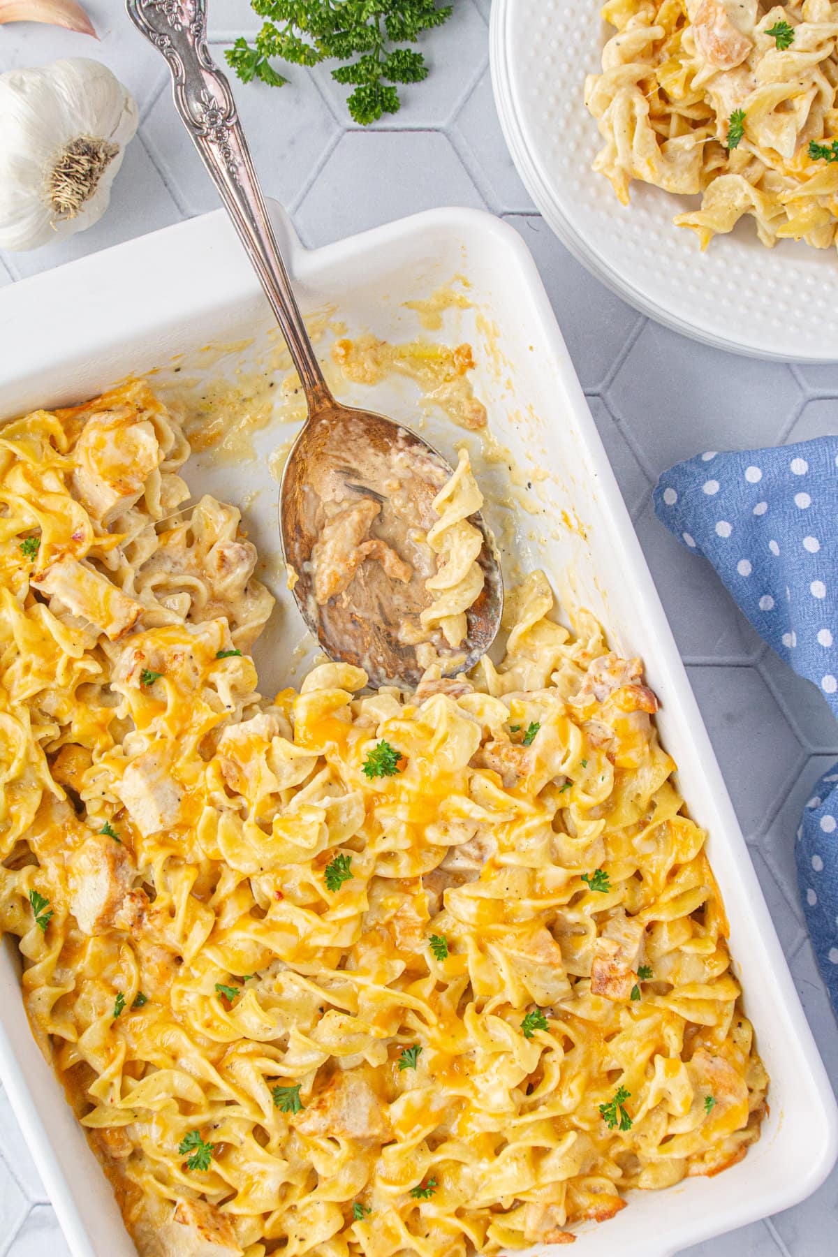 Angel chicken and noodles casserole with one scoop portioned out onto a plate to the side.