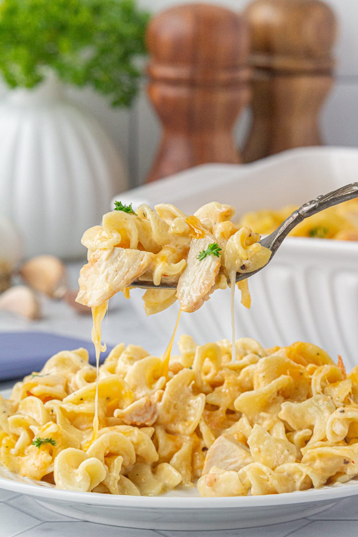 An up-close view of angel chicken and noodles casserole on a fork and dinner plate.