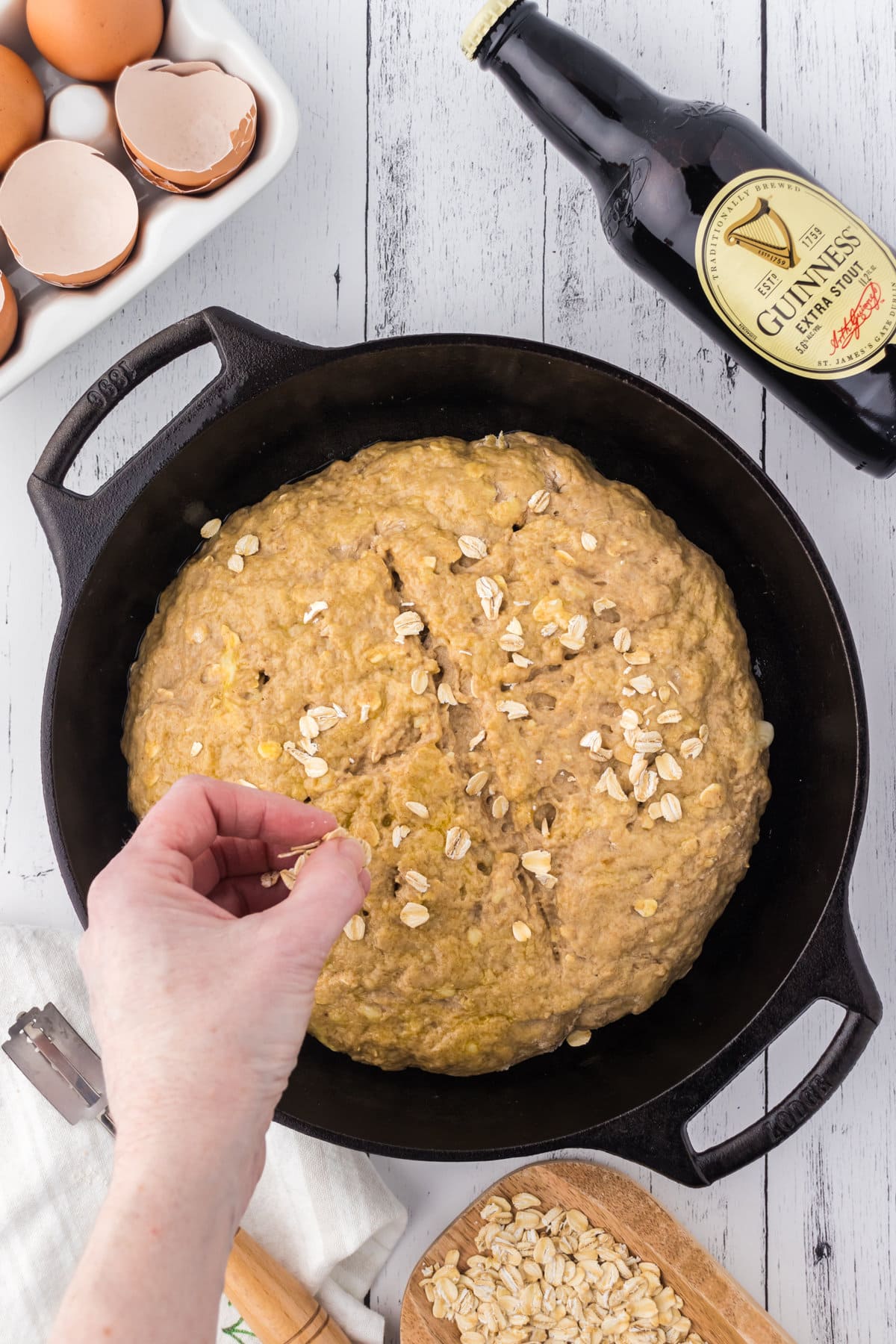 Shaped dough being sprinkled with oatmeal before baking.