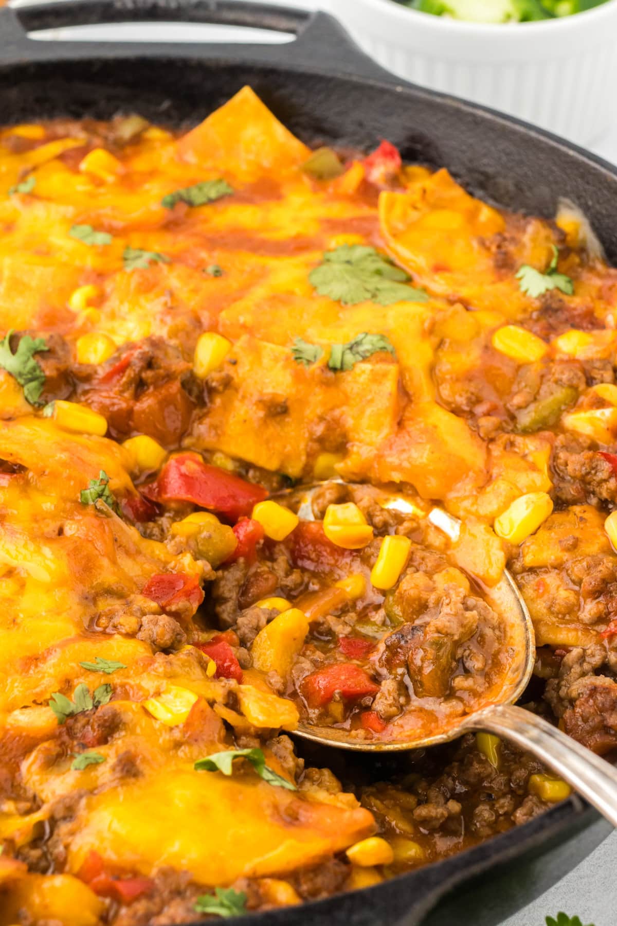 A close-up view of skillet beef tamales with a serving spoon scooping some out.