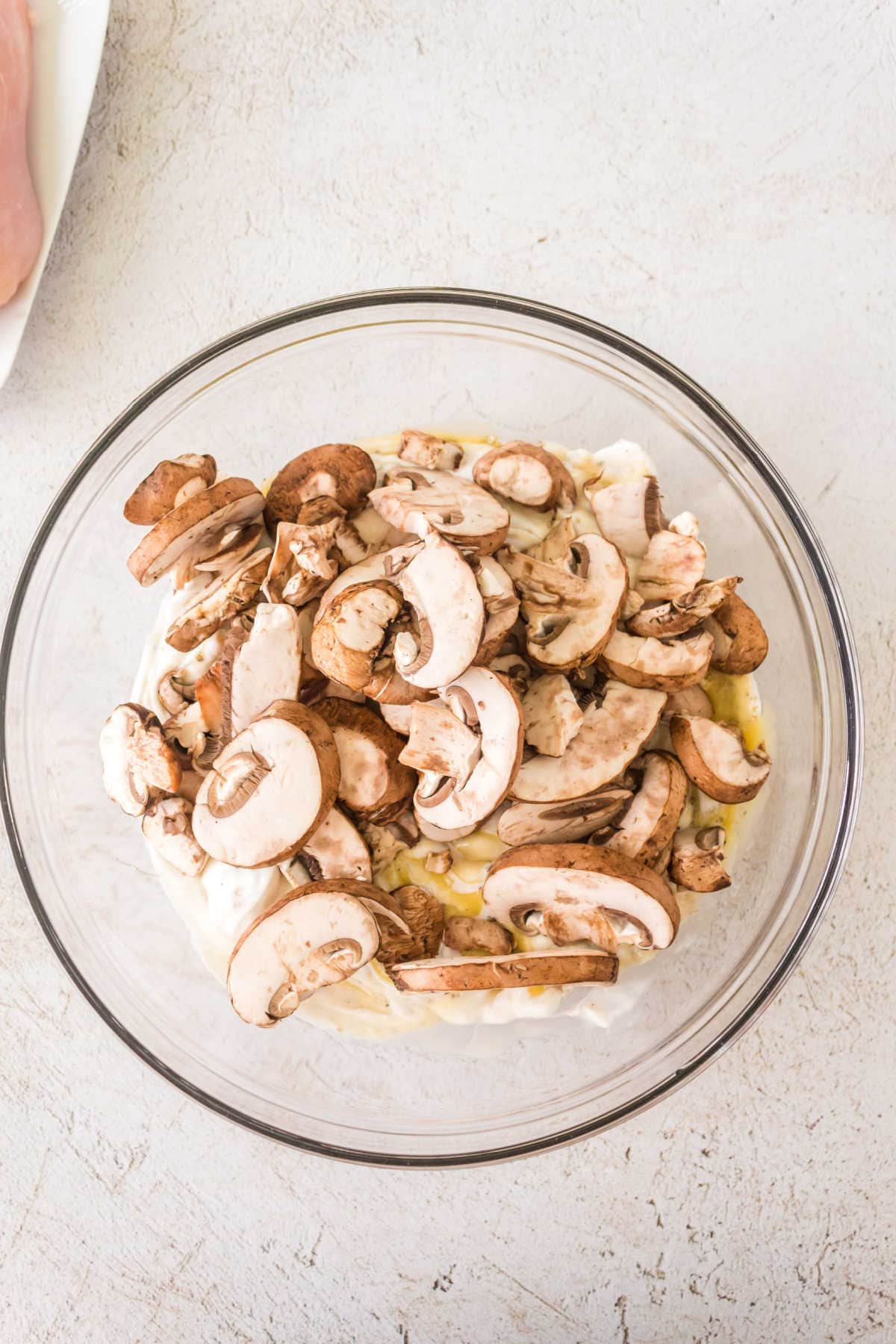 Sliced mushrooms added to the glass bowl with the soup mixture.