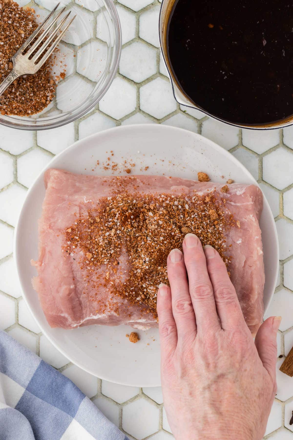 Dry rub being patted onto the pork loin.