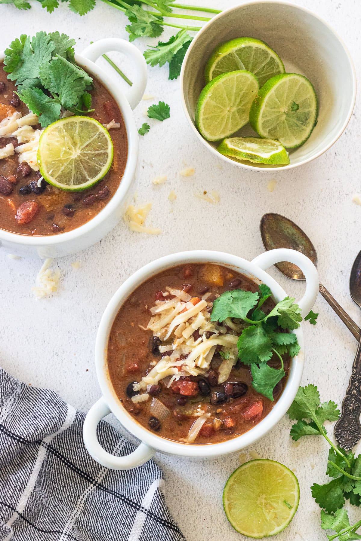 Overhead view of two bowls of black bean soup garnished with lime.