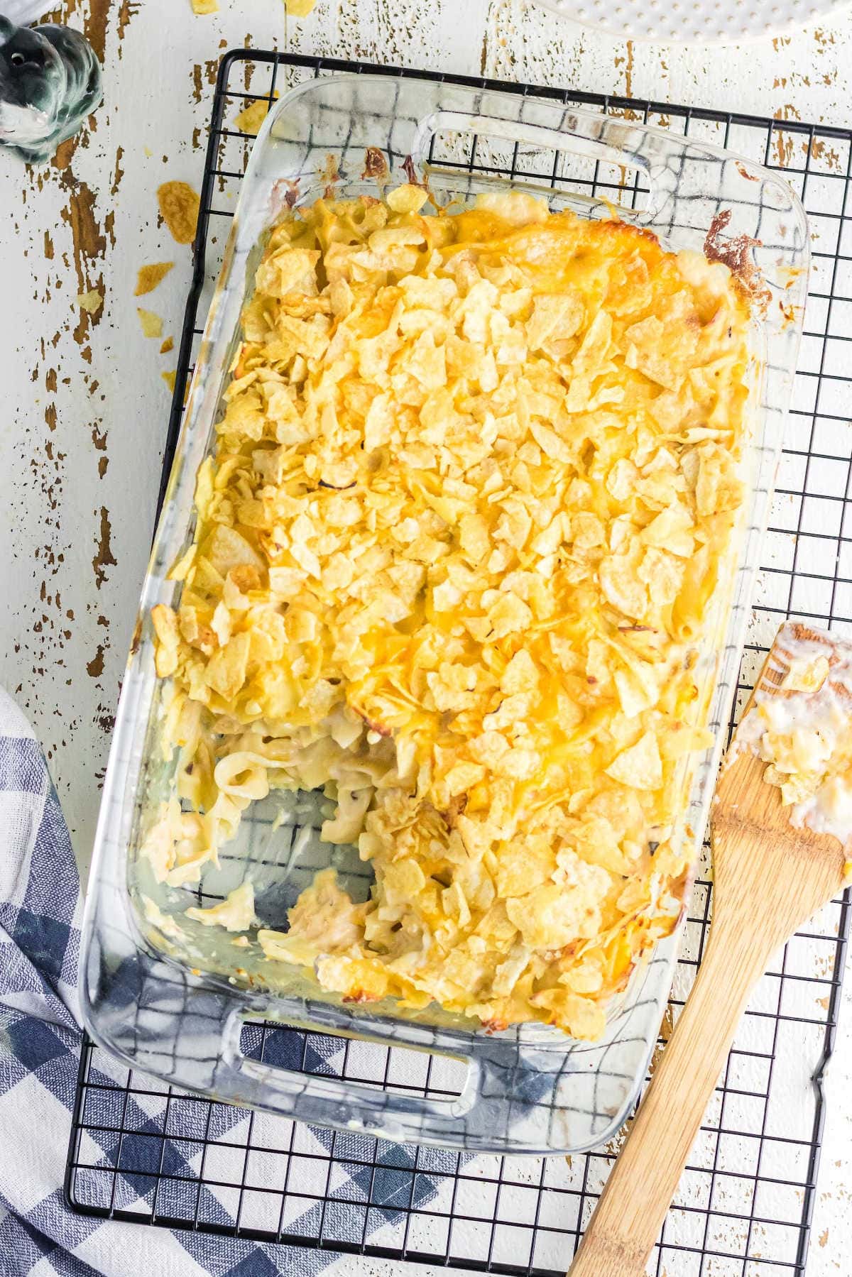 Overhead view of tuna casserole with potato chips on top. A serving has been removed to show the creamy noodles and tuna mixture.