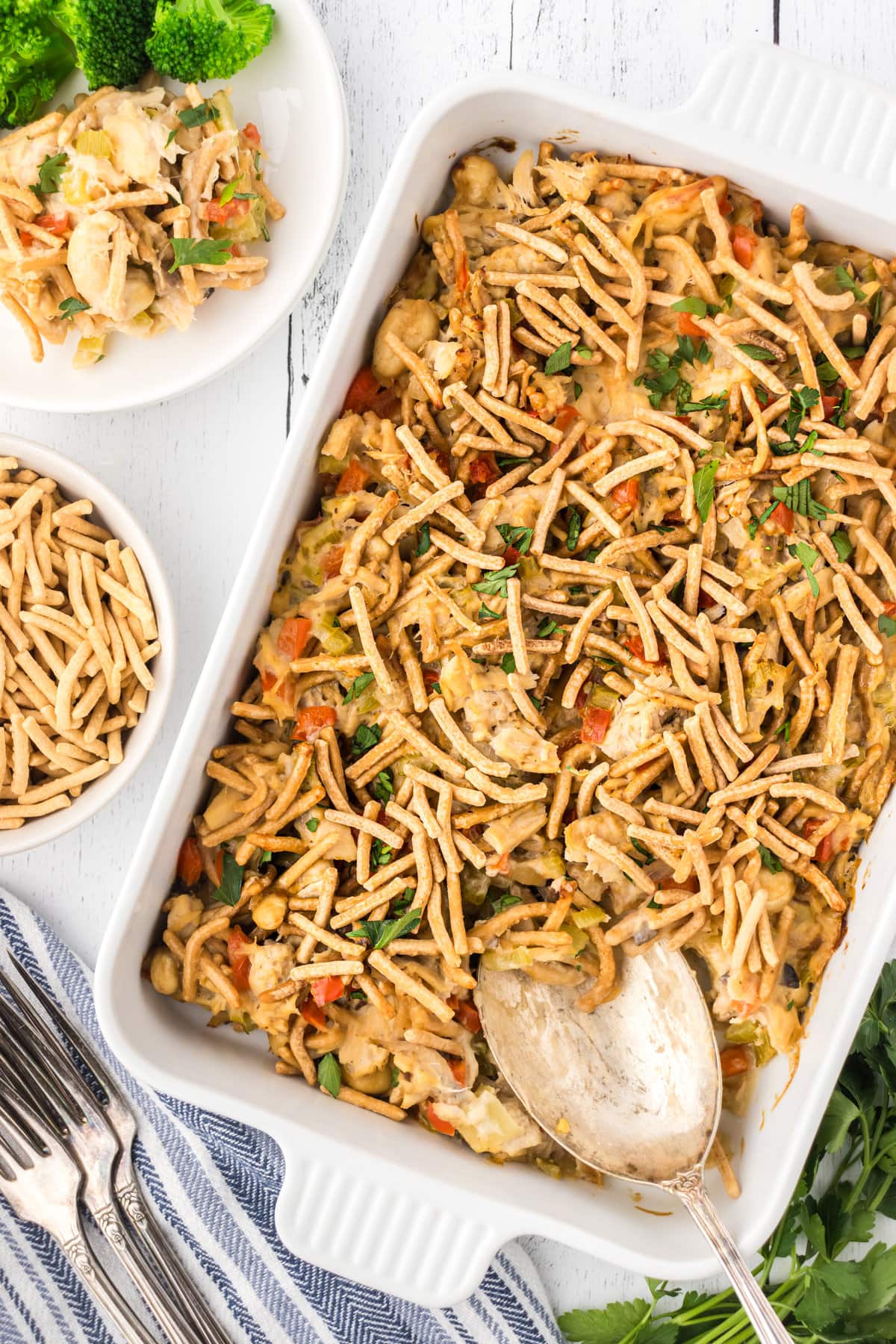 An overhead view of chopstick tuna casserole in a baking dish with a serving spoon.