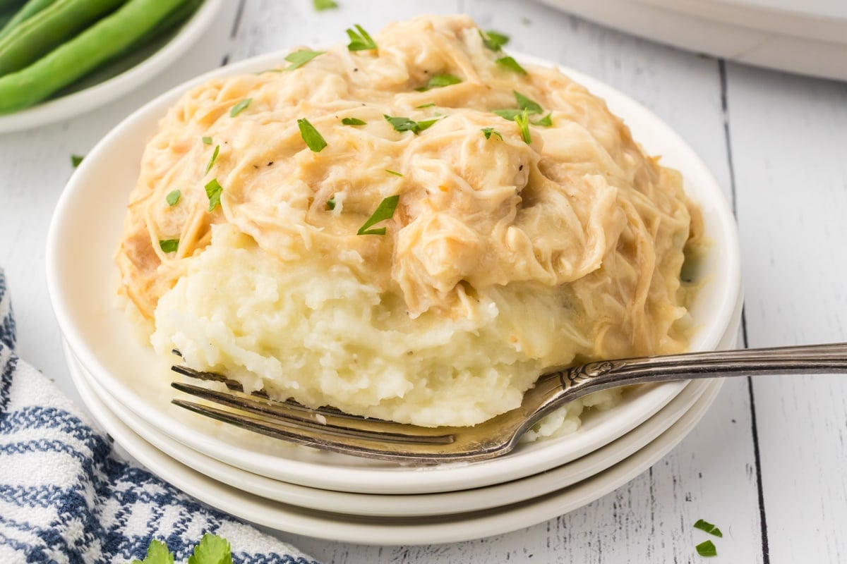 A plate filled with chicken and gravy over mashed potatoes. 