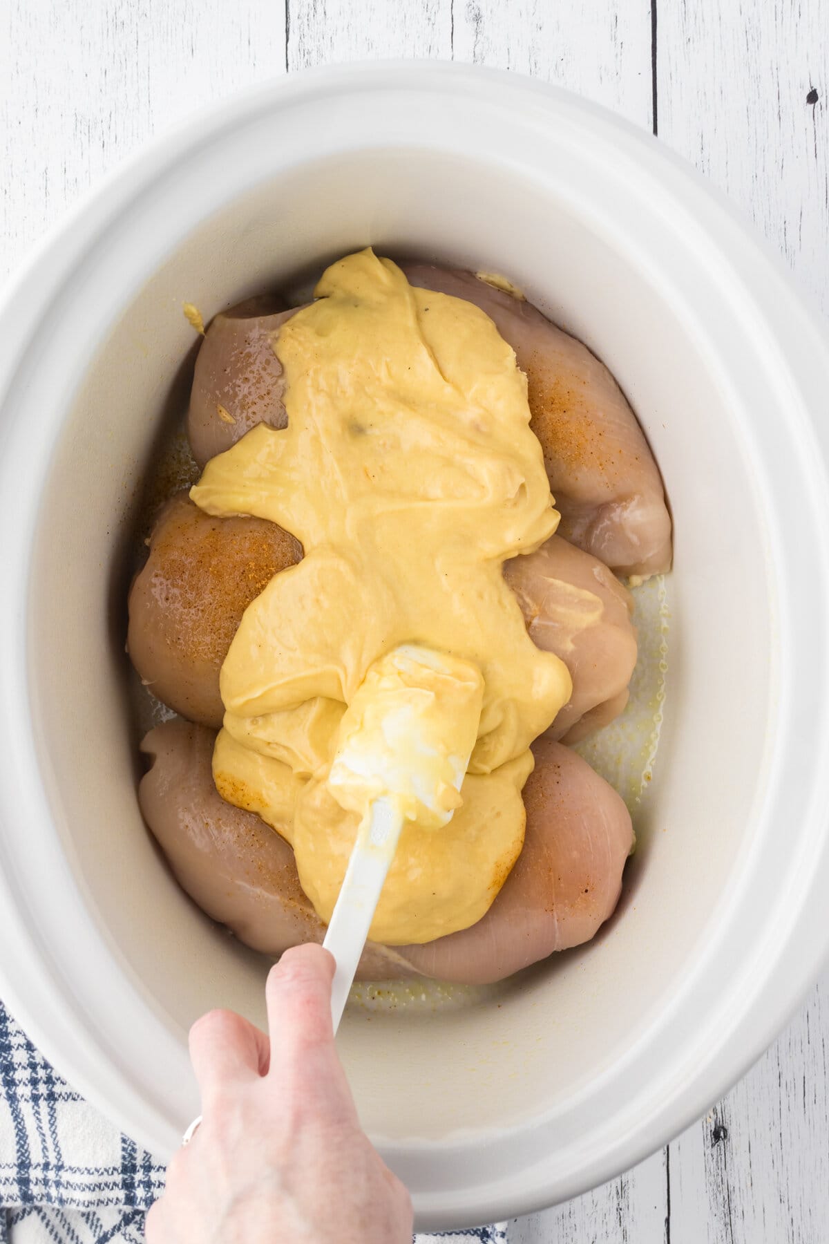 Spooning the soup mixture over the top of the chicken.