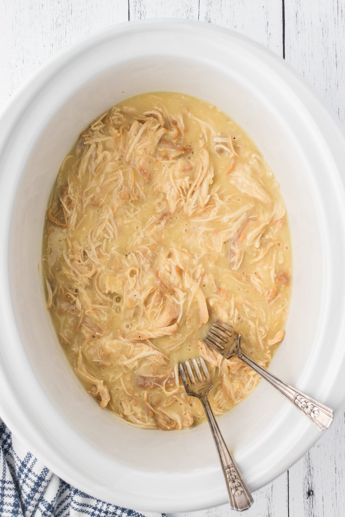 Overhead view of the chicken being shredded with two forks.