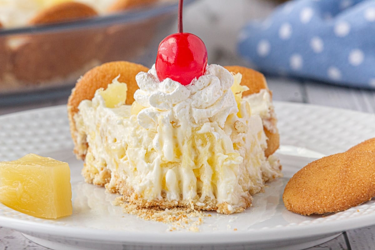 A close-up view of fluffy pineapple pie on a plate with a forkful missing.