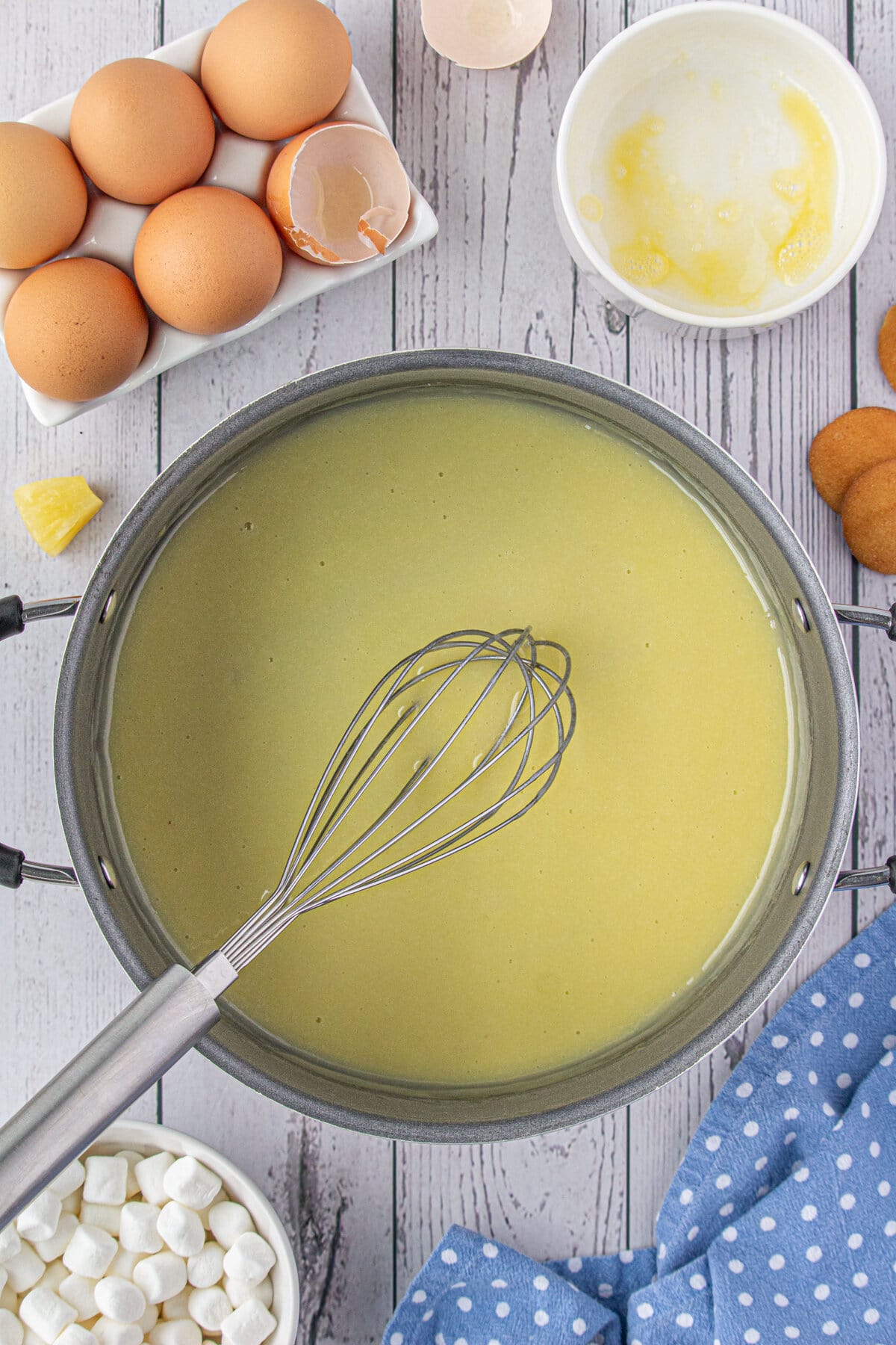 Tempering the egg with the hot syrup mixture.