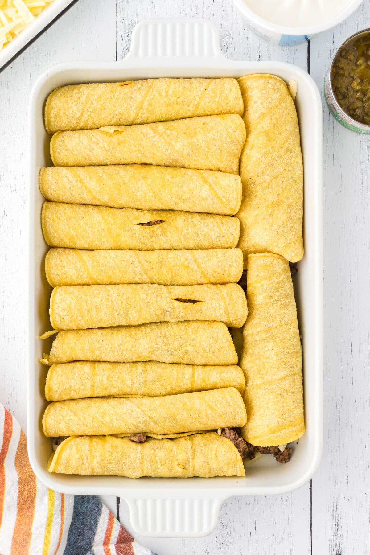 Rolled enchiladas in a baking dish.