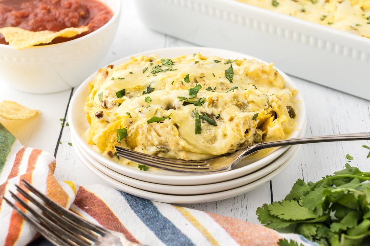 Creamy green chile enchiladas on a dinner plate with a fork.