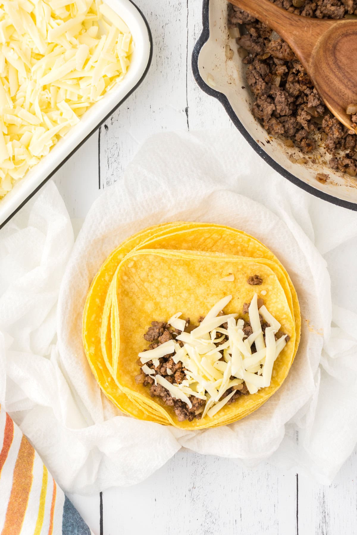 Enchilada filling and cheese on a corn tortilla.