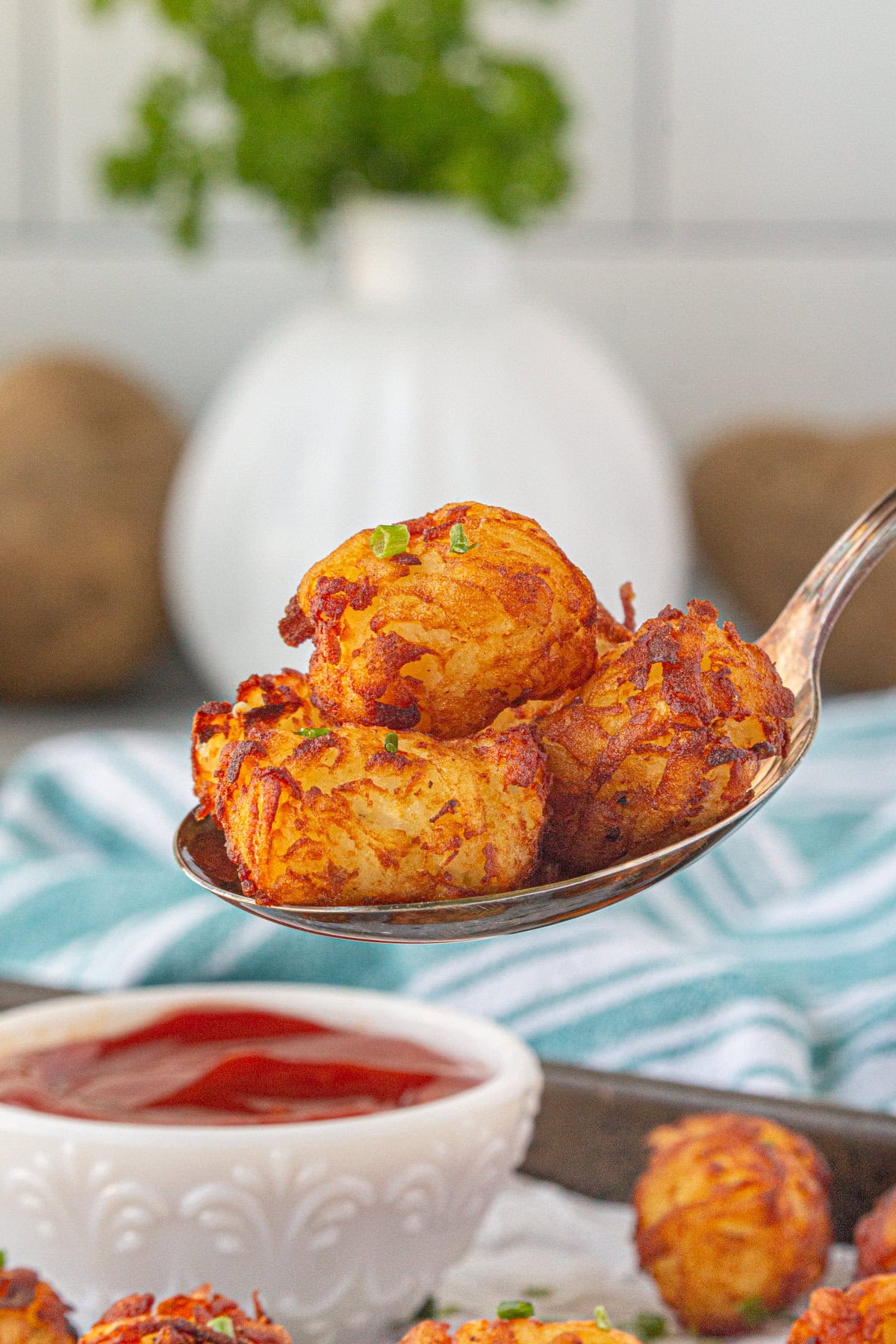 A serving spoon filled with crispy, golden-brown, homemade tater tots.