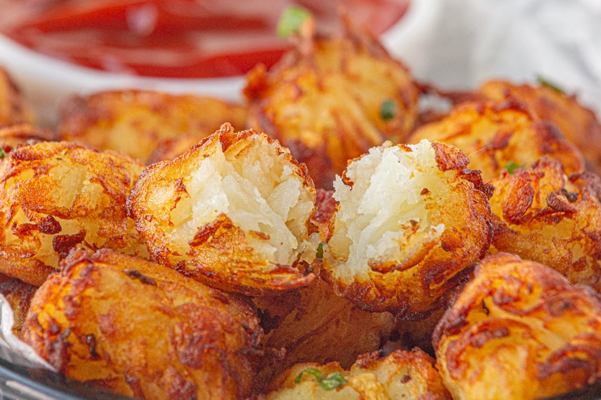 Closeup of homemade tater tots with one broken open to see the inside.