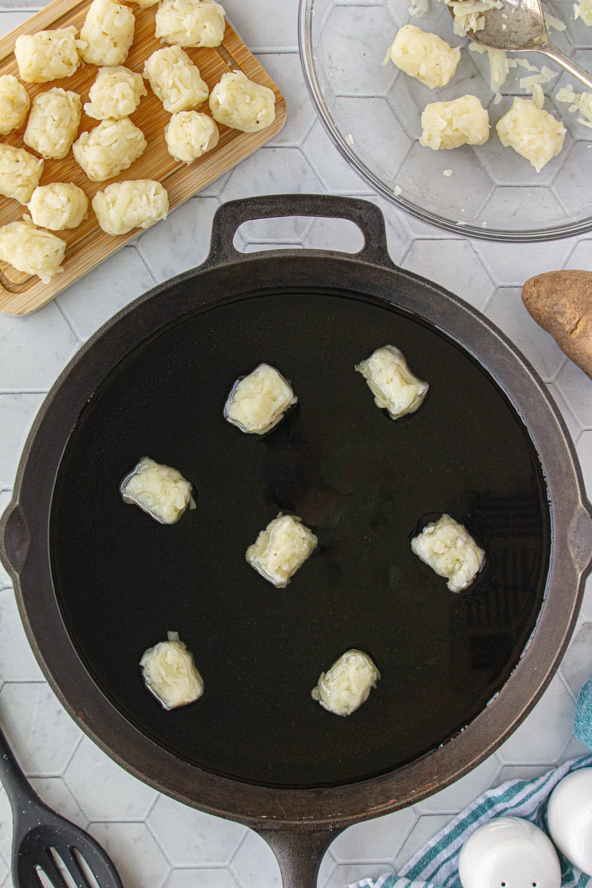 Homemade tater tots cooking in a pan.