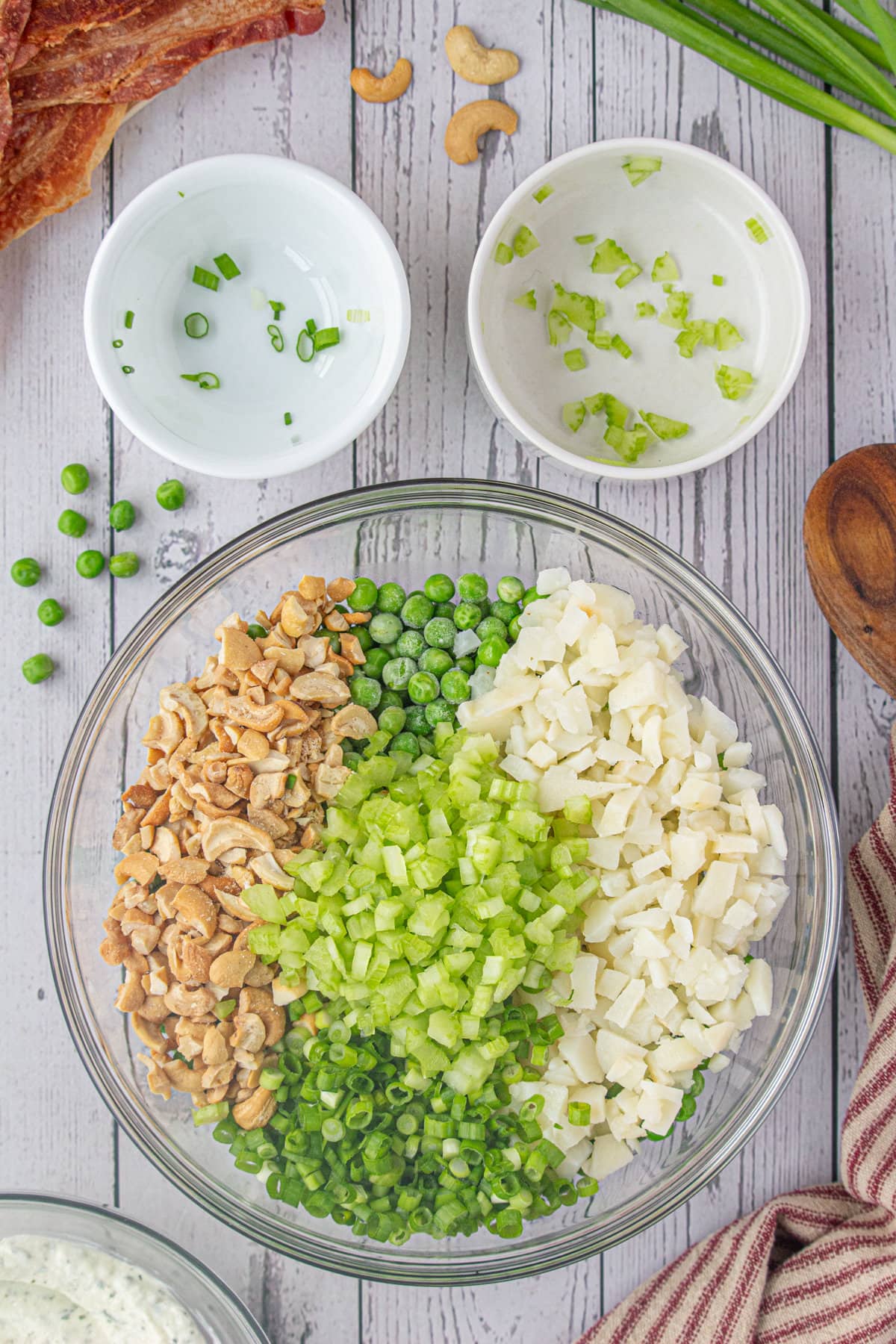 The peas, onions, celery, cashews, and water chestnuts in a large bowl.