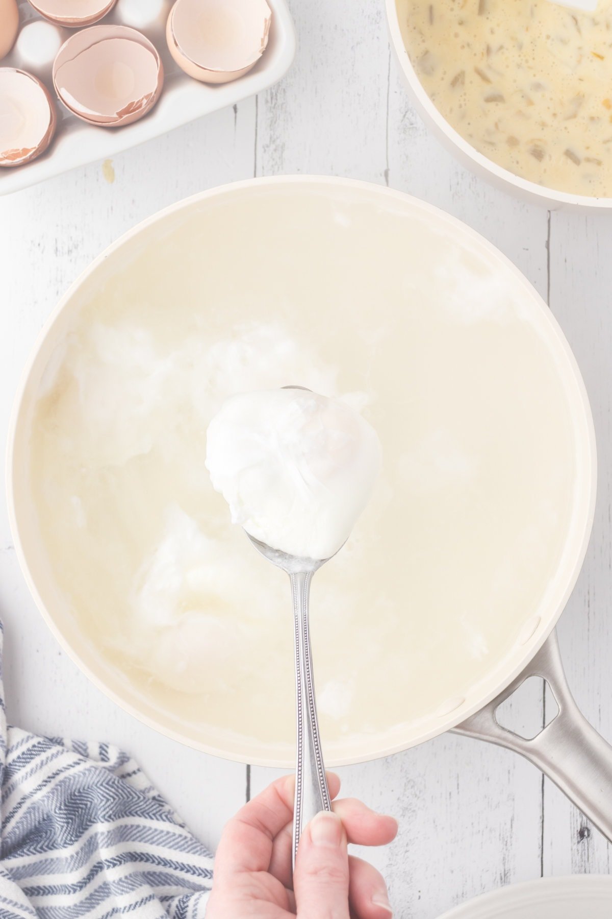 Removing the poached egg with a slotted spoon.