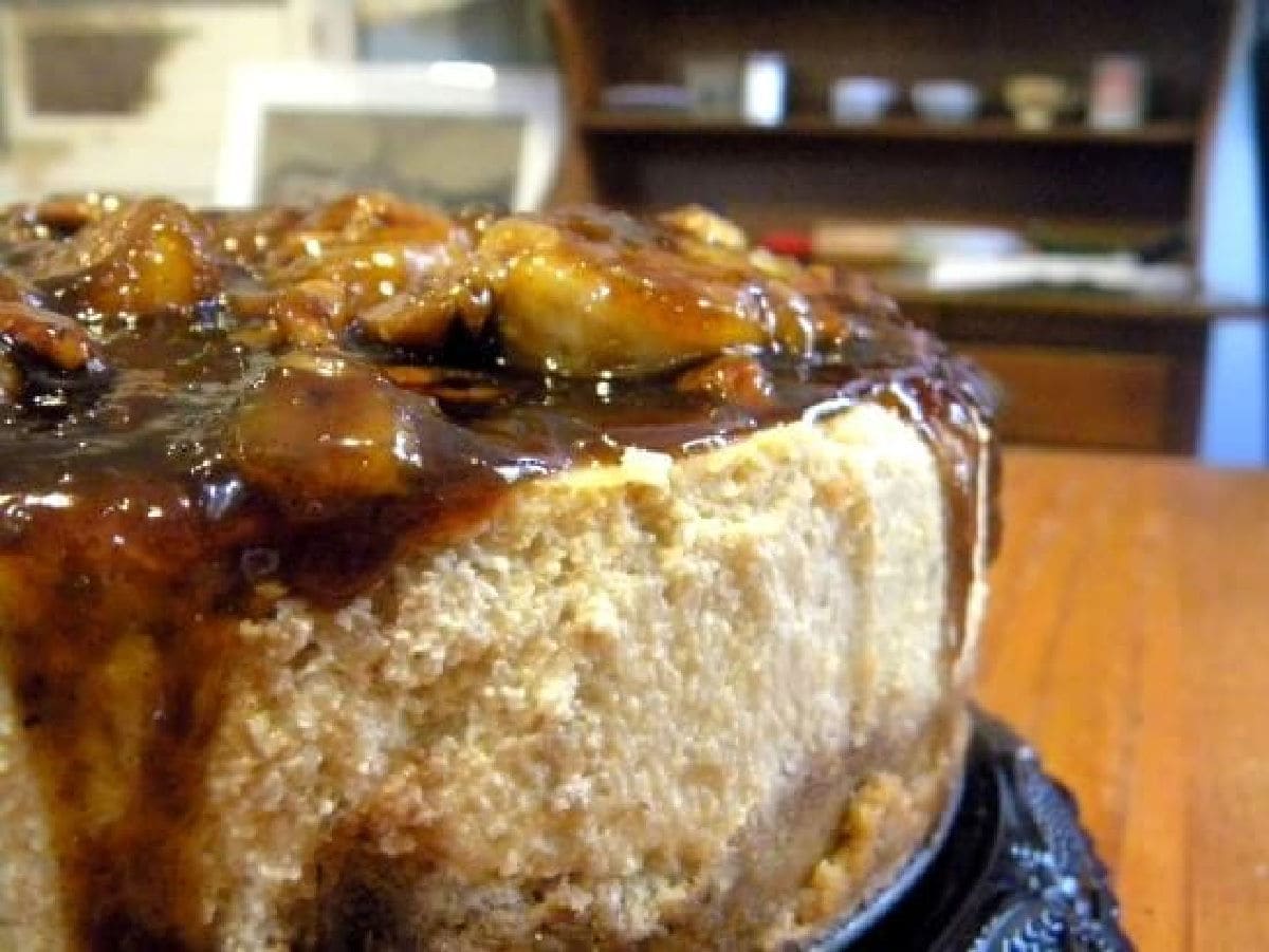 Closeup of banana foster cheesecake with a bourbon caramel glaze and bananas on top.