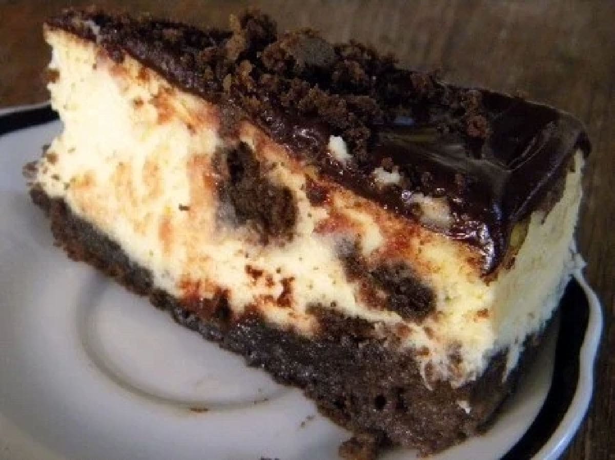 A slice of brownie cheesecake on a plate.