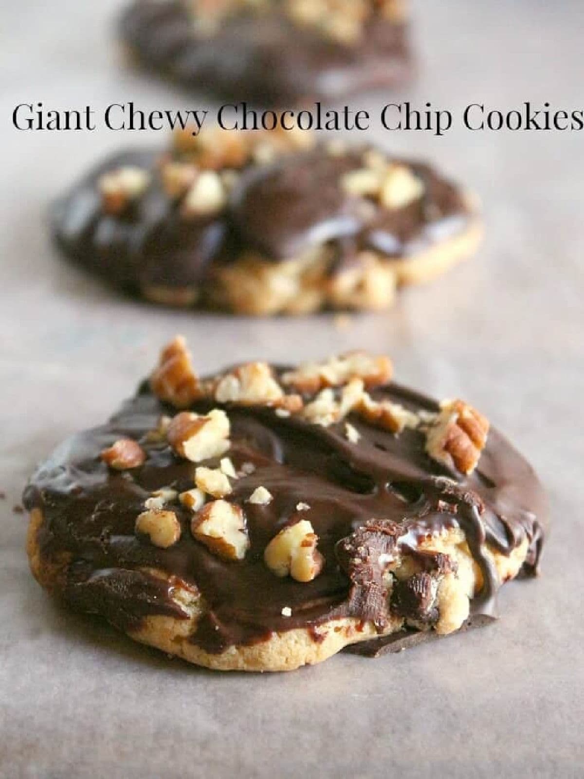 Closeup of chocolate chip cookies with chocolate and pecans on the top.