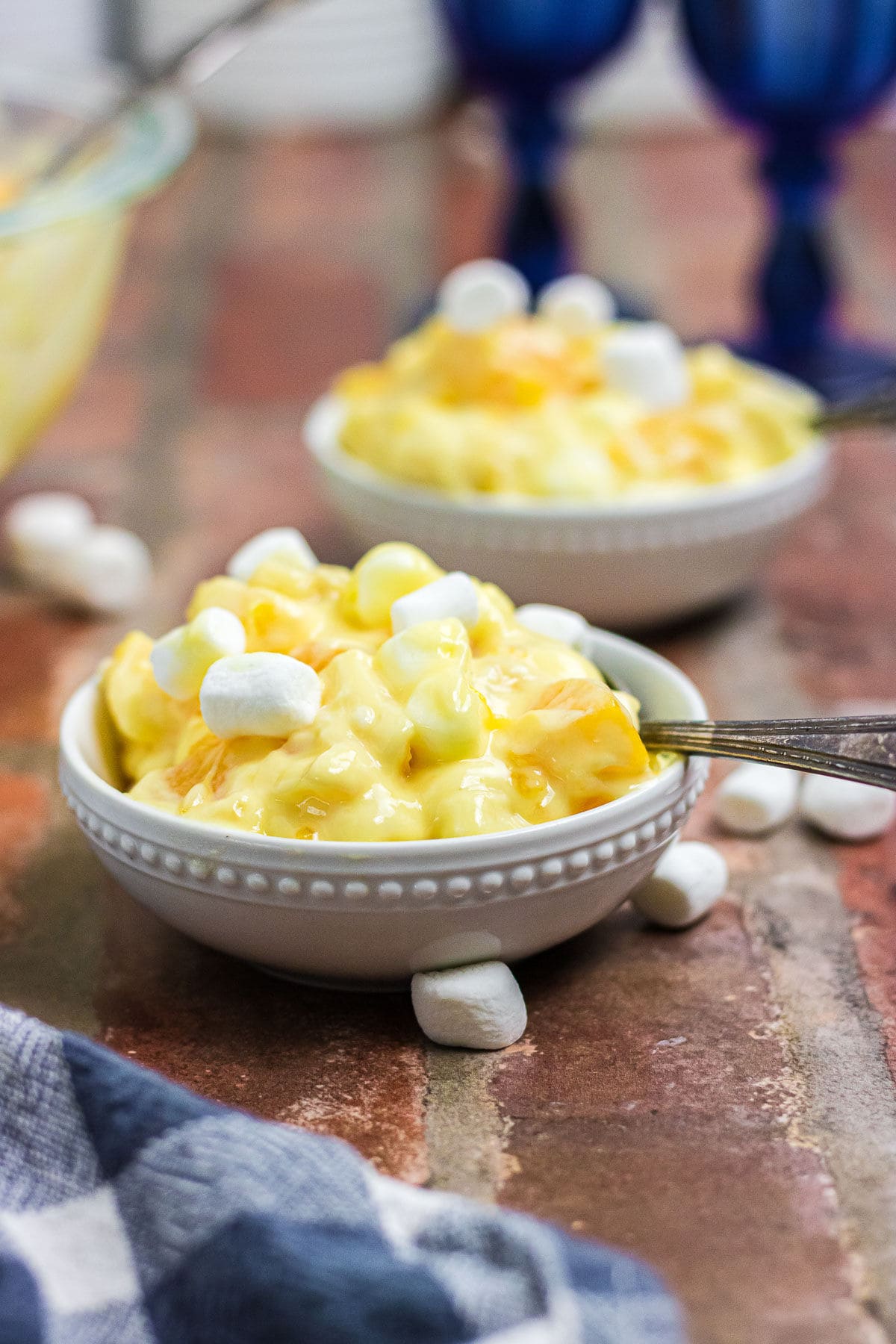 Two small serving dishes of orange cream salad on a brick countertop.