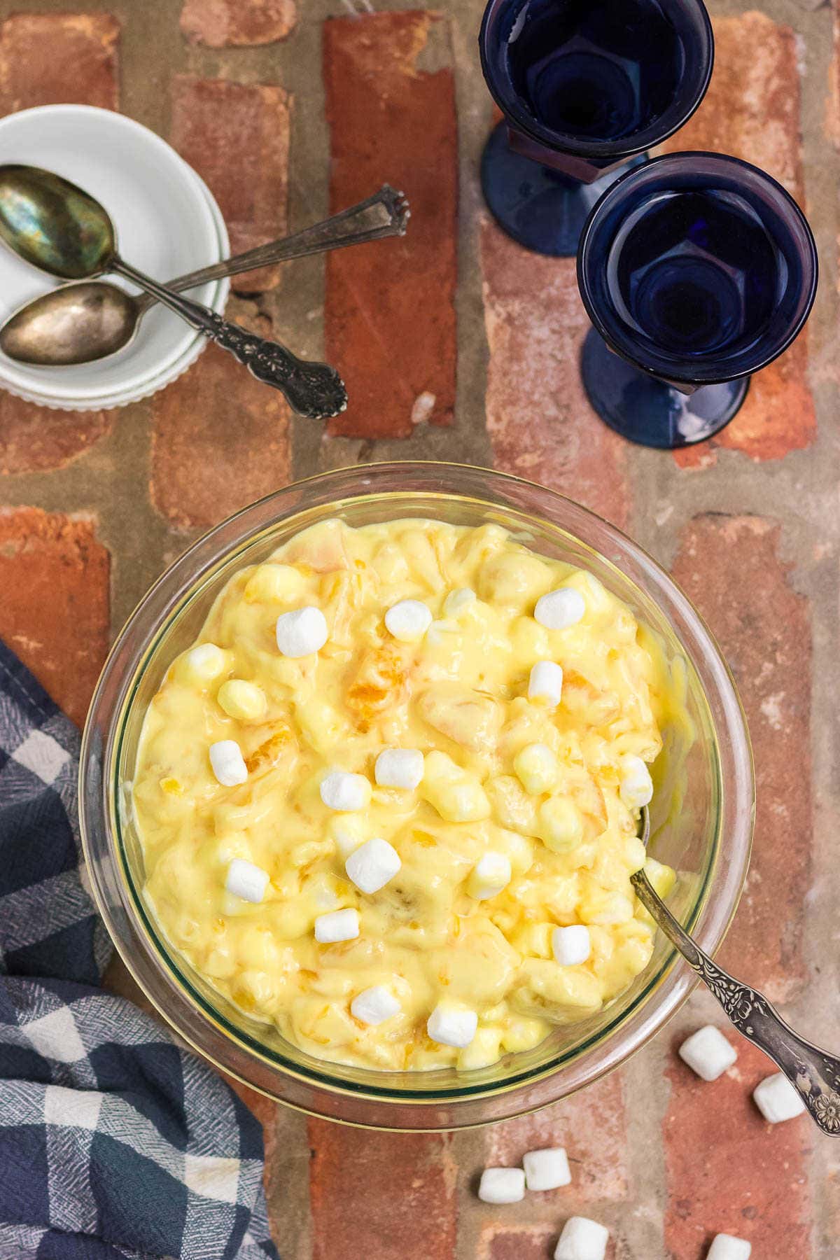 Overhead view of orange cream salad with marshmallows on top on a brick countertop.