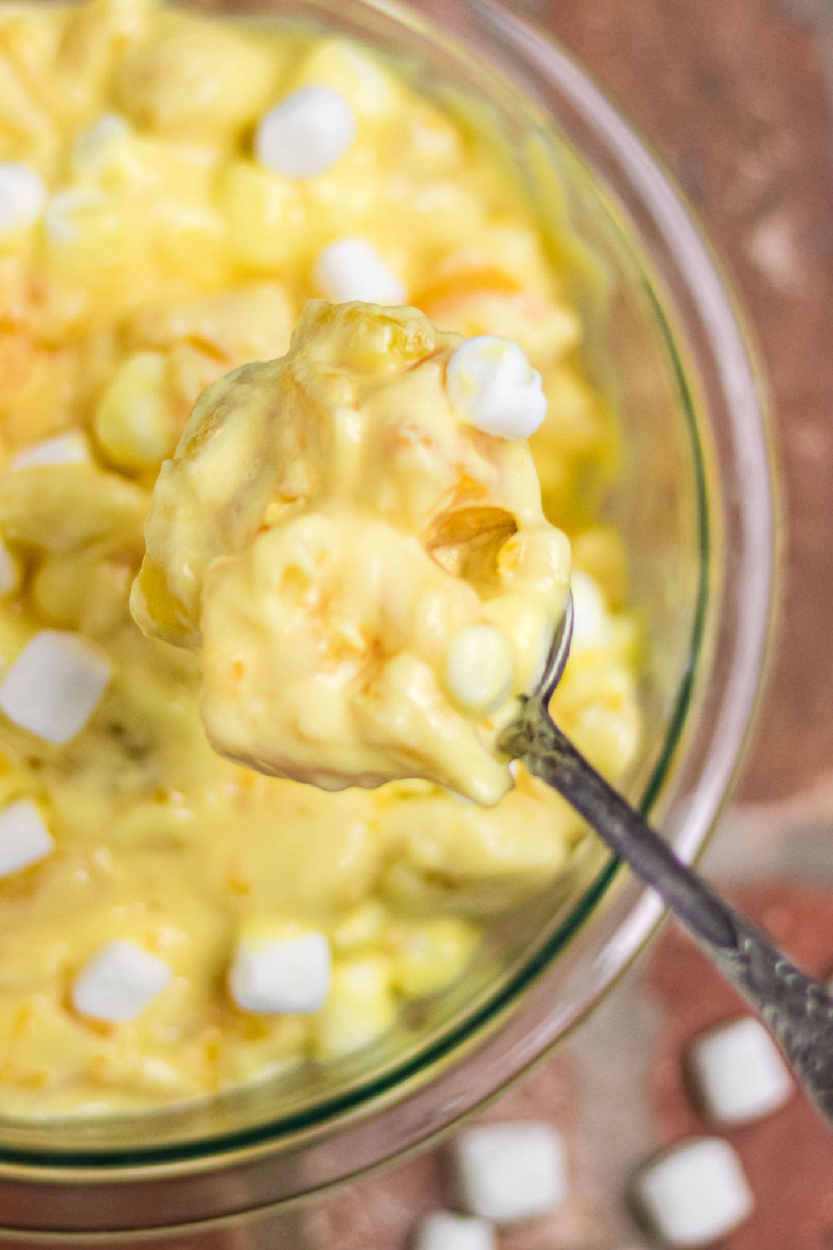 A spoonful of the orange cream salad being lifted from a bowl.