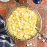 Overhead view of orange cream salad with a serving spoon in it.