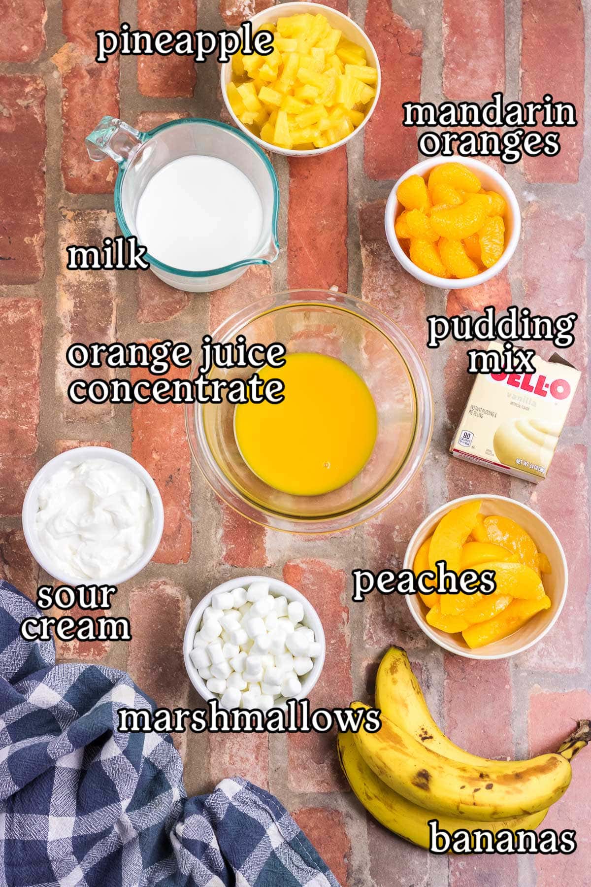 Labeled ingredients for orange cream salad: mandarin oranges, milk, pudding mix, orange juice concentrate, sour cream, marshmallows, peaches, bananas, pineapple.